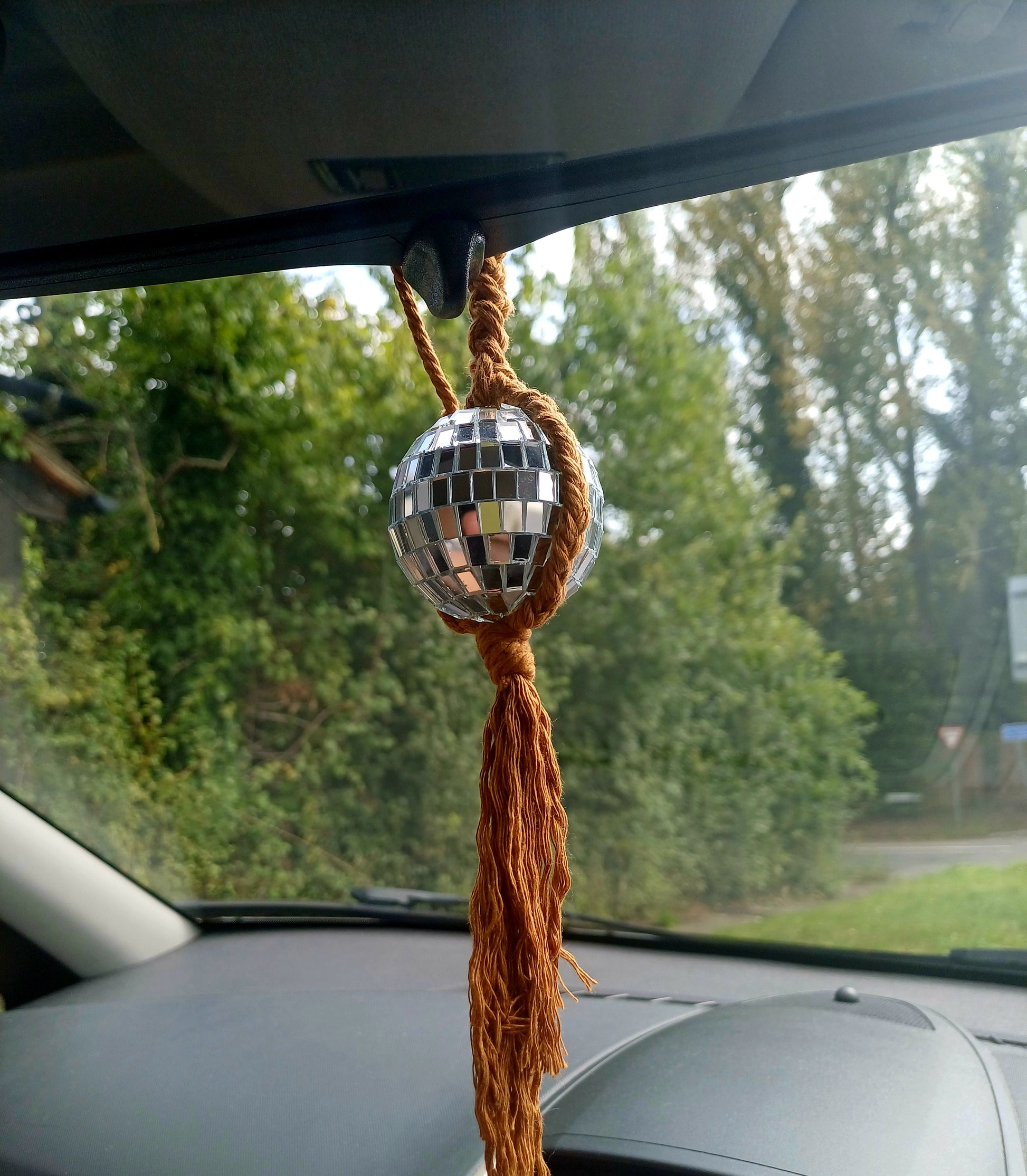 Mini disco balls with adjustable ties hanging from a car rear view mirror